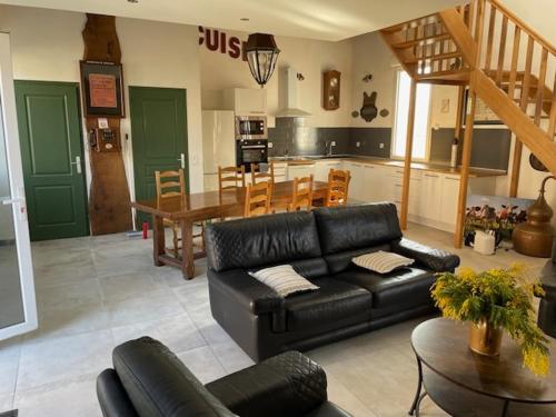 a living room with a black leather couch and a table at La scierie Massonat in Cossaye