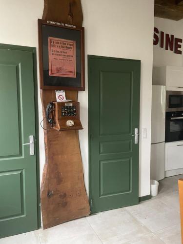 two green doors in a kitchen with a clock on the wall at La scierie Massonat in Cossaye