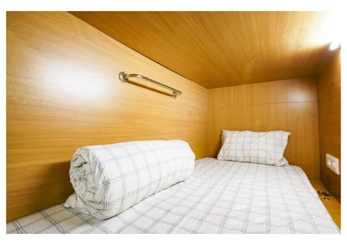 a small bed in a room with a wooden wall at The Pune Story in Pune