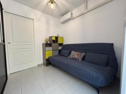 a living room with a blue couch and a door at Le Montille - Appartement face au Port - Climatisation et Wifi in Port-la-Nouvelle