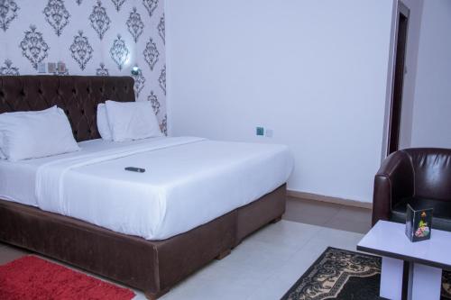 a bedroom with a large bed and a chair at Zoey International Hotels Ltd in Owerri