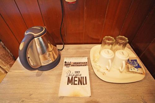 a table with a tea kettle and a book on it at Whispering Woods Inn - Stay & Enjoy in Nature ! in Bolpur