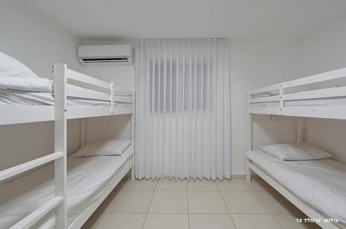 a room with three bunk beds and a radiator at וילה ויליז'ן in H̱azon