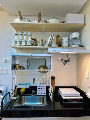 a kitchen with a sink and shelves with pans at Auberge Condotels B at SMDC Hope Residences in Trece Martires