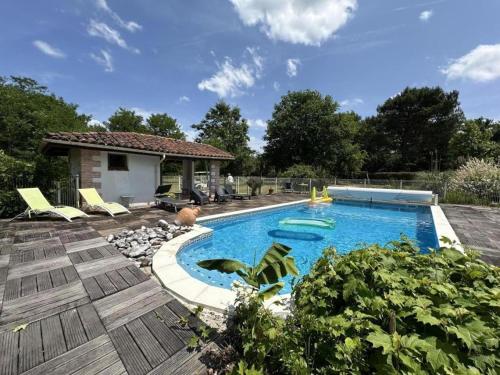 une piscine avec des chaises et une maison dans l'établissement Les lavandes, à Mézos