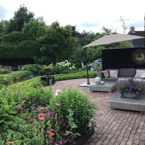 a patio with a couch and some flowers and an umbrella at Appartement de Tuinkamer in Ter Apel