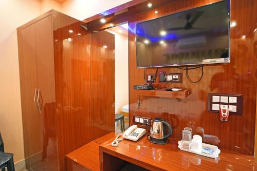 a room with a desk with a phone and a tv at Whispering Woods Inn - Stay & Enjoy in Nature ! in Bolpur