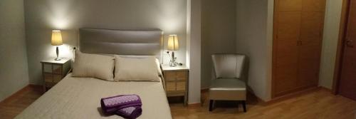 um quarto com uma cama grande e uma cadeira em Apartamento Capitania em Granada