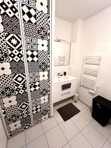 La salle de bains est pourvue d'un mur noir et blanc à motifs. dans l'établissement 2-room apartment, bright balcony, à Nice