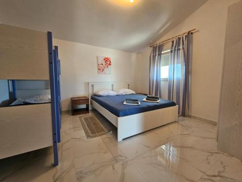 a bedroom with a bed with blue sheets and a window at Apartments Marija in Vir