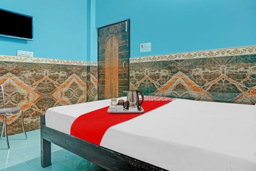a bedroom with a bed with a red blanket and a tv at Hotel O B K Brothers in Gulzārbāgh