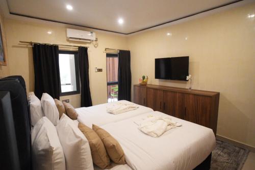 a bedroom with a bed with white sheets and a flat screen tv at Almadies Prestige in Parakou