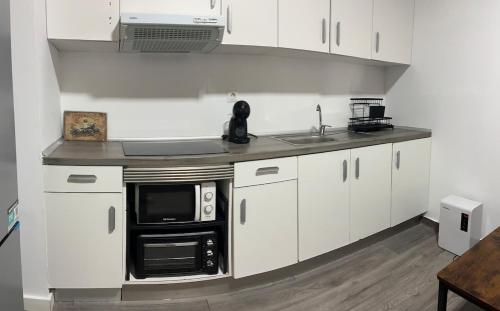 a kitchen with white cabinets and a sink and a microwave at 150m from the beach in Barcelona