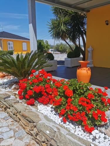 a flower bed with red flowers in a yard at A Flor da Rosa in Vila Nova de Foz Coa