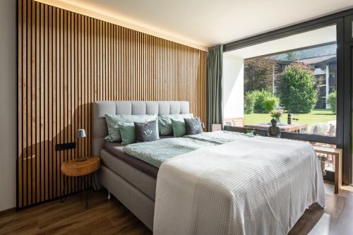 a bedroom with a large bed and a large window at Schlosspark Grubhof - Mitterer in Sankt Martin bei Lofer