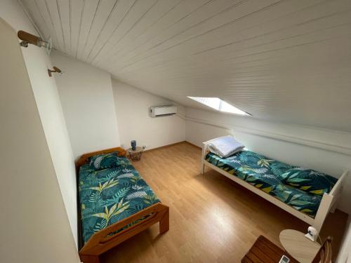 Cette chambre mansardée comprend 2 lits et une fenêtre. dans l'établissement Demi maison avec terrasse et jardin 3 chambres 6 pers, à Royan