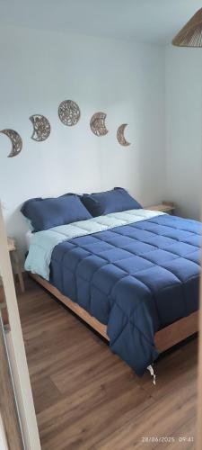 - un lit avec une couette bleue dans une chambre dans l'établissement Gîte Terre et Mer, 