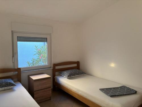 two twin beds in a room with a window at Apartmani Ruža in Vir