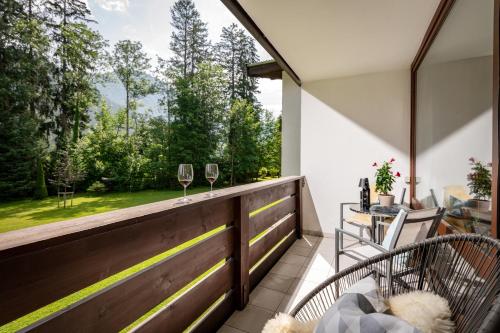 a balcony with wine glasses and a table and chairs at Schlosspark Grubhof - Mitterer in Sankt Martin bei Lofer