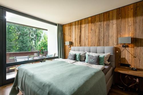 a bedroom with a large bed and a large window at Schlosspark Grubhof - Mitterer in Sankt Martin bei Lofer