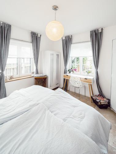 a bedroom with a large white bed and windows at Alpenrausch 1 in Kiefersfelden