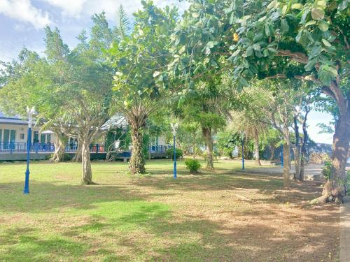 a park with trees and grass with a house in the background at Love at First Sight in Chumphon
