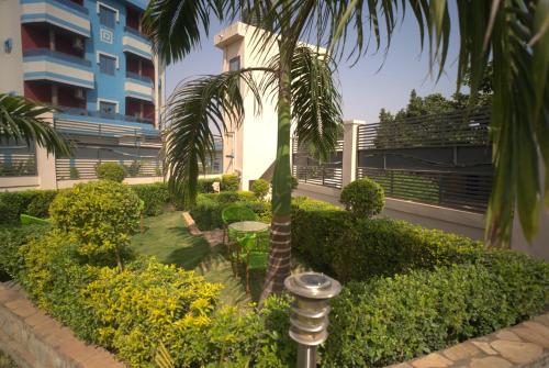a garden with a palm tree in front of a building at Almadies Prestige in Parakou