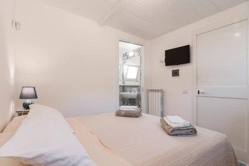 a white bedroom with a bed and a window at LA CESA Holiday House in San Felice Circeo