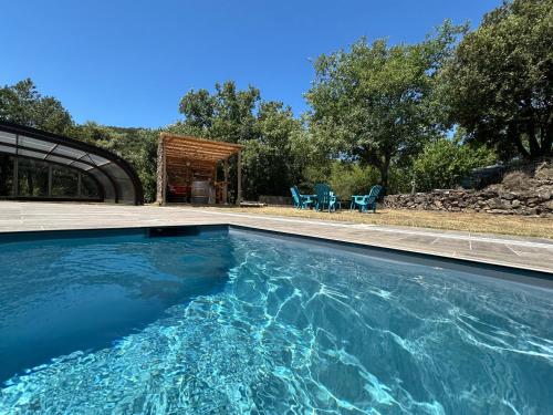 - une piscine en face d'une maison avec 2 chaises dans l'établissement Gîte Le Cèdre, à Beauchastel