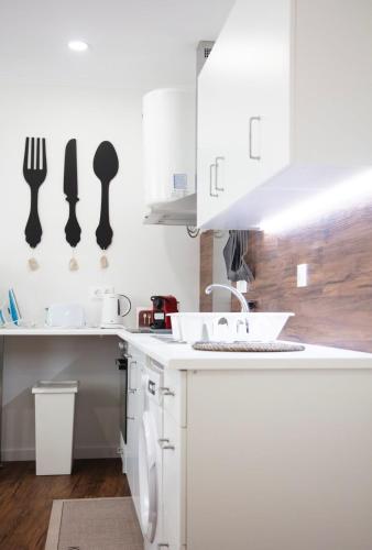 a white kitchen with a sink and utensils on the wall at Cristal apartamento 1 esq Monte Brasil in Angra do Heroísmo