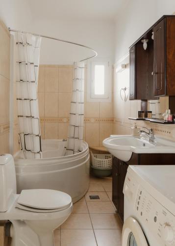 a bathroom with a tub and a toilet and a sink at Villa Eros in Vátos