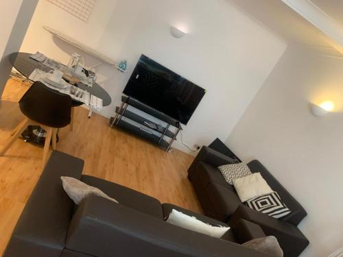 un soggiorno con divano nero e TV di The Oxford St Stay a Londra