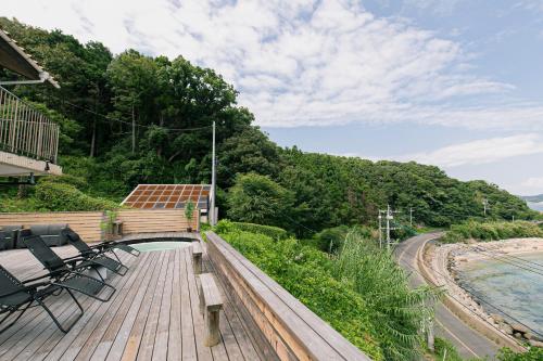 a deck with chairs and a bridge over the water at Villa Classico Itoshima in Itoshima