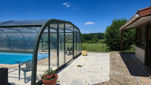 une serre en verre à côté d'une piscine dans l'établissement maison a la campagne avec piscine, à Flayat