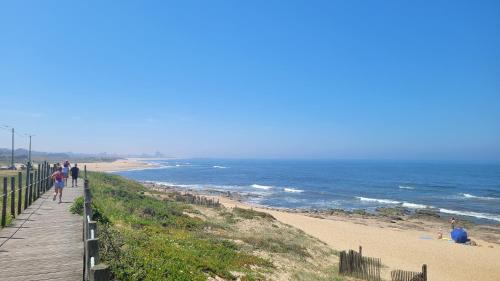 a boardwalk leading to a beach with people walking on it at Granja Beach Front in São Félix da Marinha