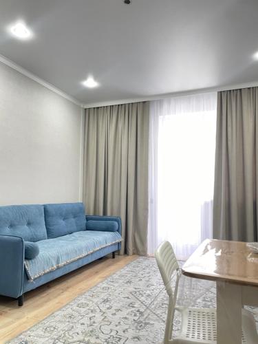 ein Wohnzimmer mit einem blauen Sofa und einem Tisch in der Unterkunft Двухкомнатная квартира in Astana