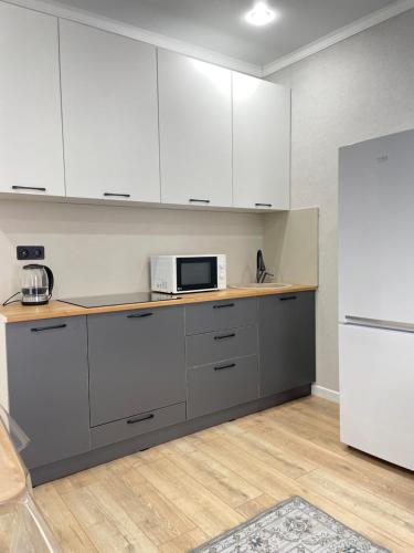 eine Küche mit weißen Schränken und einer Mikrowelle in der Unterkunft Двухкомнатная квартира in Astana