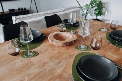a wooden table with black plates and wine glasses at NEU Zweiraumstil I Modernes Design I voll ausgestattet I Sehr ruhige Lage I Arbeitsplatz I Hotelbetten I Smart TV mit Netflix und Magenta I Frisch saniert in Bad Bevensen