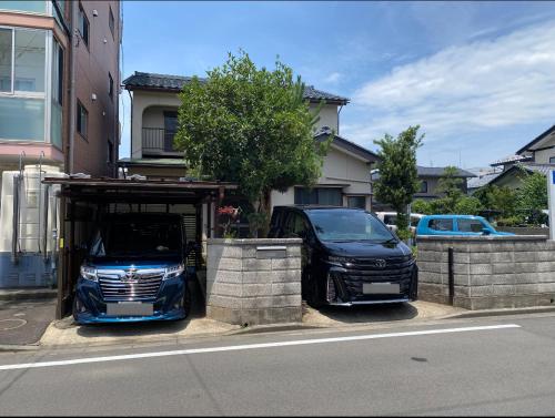 two cars parked under a carport on a street at 貸切民泊 手寄の宿 JR福井駅東口から徒歩5分 5min 安い in Fukui