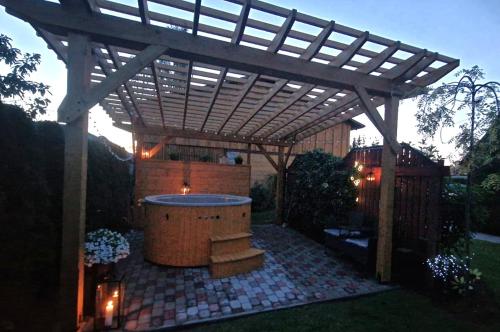 Una pérgola de madera con jacuzzi en un patio. en Atpūta Mālpilī, en Mālpils