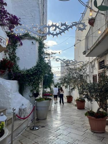 two people walking down an alley with plants and flowers at La casa di Laura in Ostuni