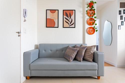 a blue couch in a living room with pictures on the wall at Apartamento - 5min do Aeroporto - Vila Telebrasília in Brasilia