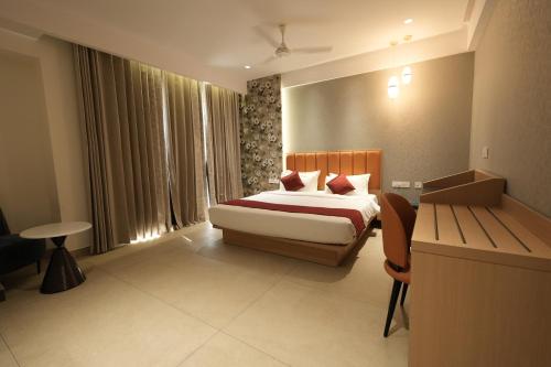 a bedroom with a bed and a desk in a room at Hotel Cachet in Coimbatore