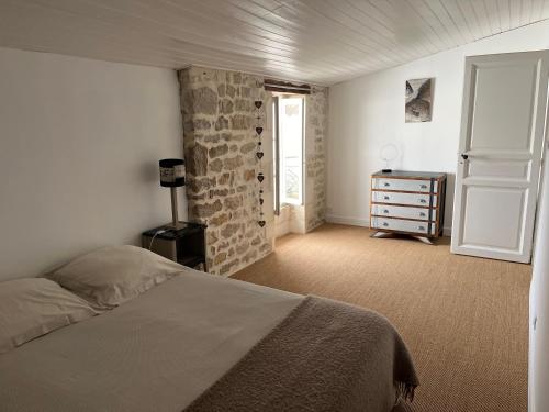 a bedroom with a bed and a dresser and a window at une fenêtre sur cour in La Flotte