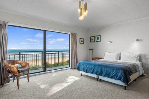 a bedroom with a bed and a large window at Beach Galore - Waihi Beach Holiday Home in Waihi Beach