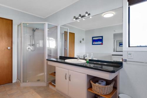 a bathroom with a sink and a shower at Beach Galore - Waihi Beach Holiday Home in Waihi Beach