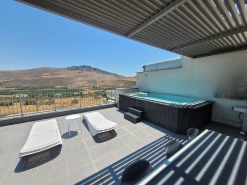 um pátio com uma piscina e 2 cadeiras brancas em Magdala Resort 2BR With private pool em Migdal