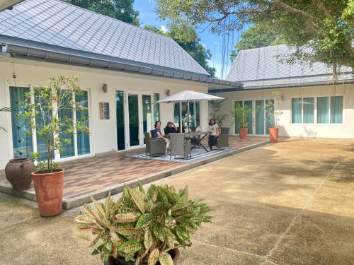 a group of people sitting under an umbrella on a patio at Love at First Sight in Chumphon
