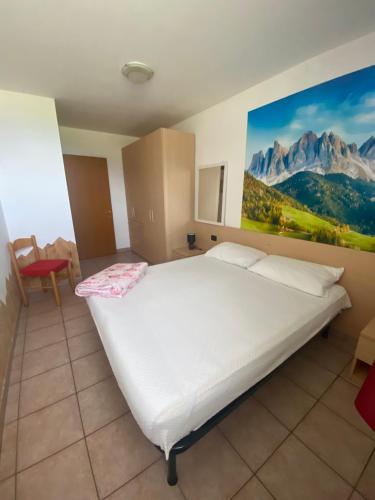 a bedroom with a large bed with a painting on the wall at Casa Mara - Agriturismo Fantelli Luciano in Dimaro