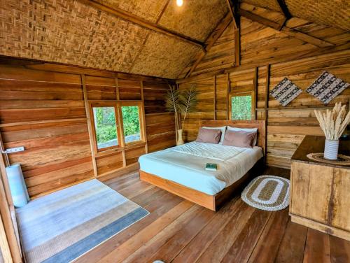 a bedroom with a bed in a log cabin at Hide and Seek in Tetebatu